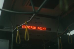 đóng vách thạch cao ngãi giao | Moody interior bus shot with 'Transfer Point' sign, featuring hanging handles.