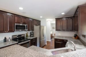 thợ đóng vách thạch cao mỹ xuân | Elegant kitchen featuring dark wooden cabinets, granite countertops, and stainless steel ap