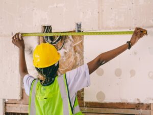 báo giá thi công trần thạch cao chống cháy vũng tàu | Female construction worker with hardhat and vest measuring an interior