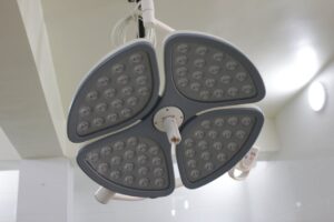 báo giá thi công trần thạch cao giật cấp phú mỹ | Close-up of a modern LED surgical lamp in a well-lit hospital room.