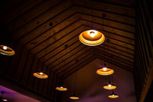 làm trần thạch cao uy tín châu đức | An indoor rustic wooden ceiling adorned with warm illuminated pendant lights.