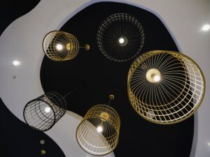 báo giá thợ thi công trần thạch cao phú mỹ | Artistic display of cage-like ceiling lights in a minimalist interior design.