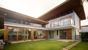 báo giá thi công trần thả mỹ xuân | Contemporary luxury house exterior with large glass windows, wooden decor, and green lawn