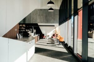 báo giá thi công trần thạch cao hiện đại phước hải | Sunlit modern café interior with minimalist decor and large windows. Per