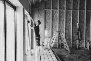 báo giá thi công trần thạch cao khách sạn long điền | Black and white photo of a worker installing drywall indoors, Falun, Sw