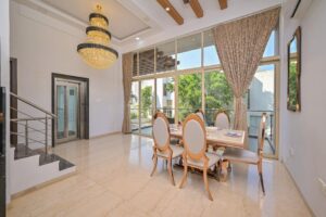 báo giá trần thạch cao chuyên nghiệp hồ cốc | Elegant dining room with a chandelier, large windows, and stylish furniture in