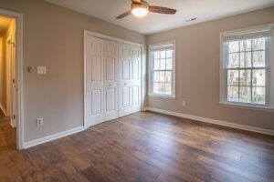 báo giá trần thạch cao giá rẻ hồ cốc | Spacious empty room with hardwood floors, ceiling fan, and natural light from windows.