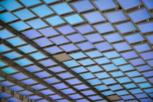 báo giá trần thạch cao phước hải | A modern ceiling installation featuring a grid of illuminated blue panels creating an abst